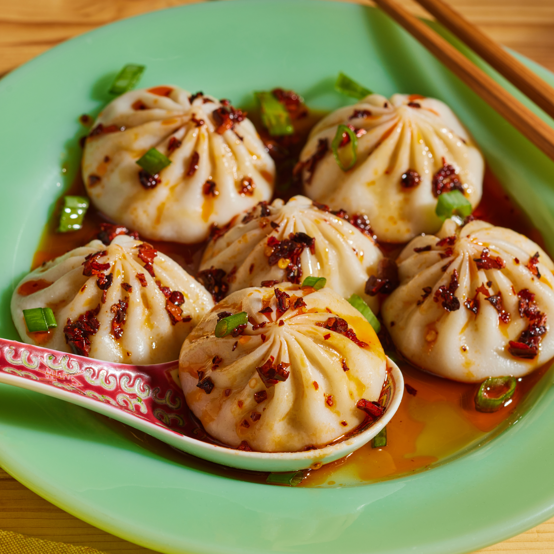 Close-up of Microwave Chicken Soup Dumplings showcasing chili crisp and scallions with a green plate