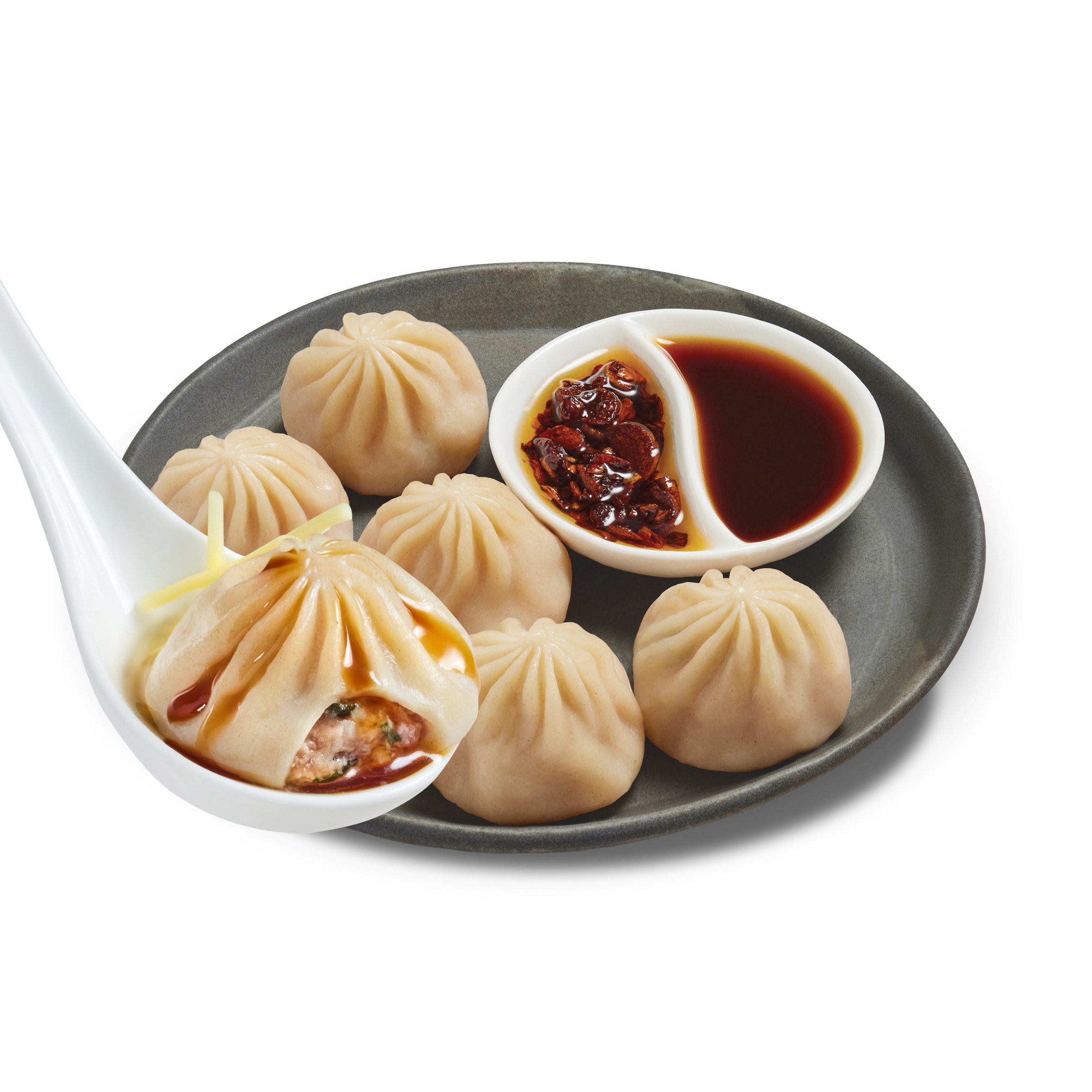 Close-up of Microwave Pork Soup Dumplings showcasing soup-filled dumplings with dipping sauce and chili crisp on a plate