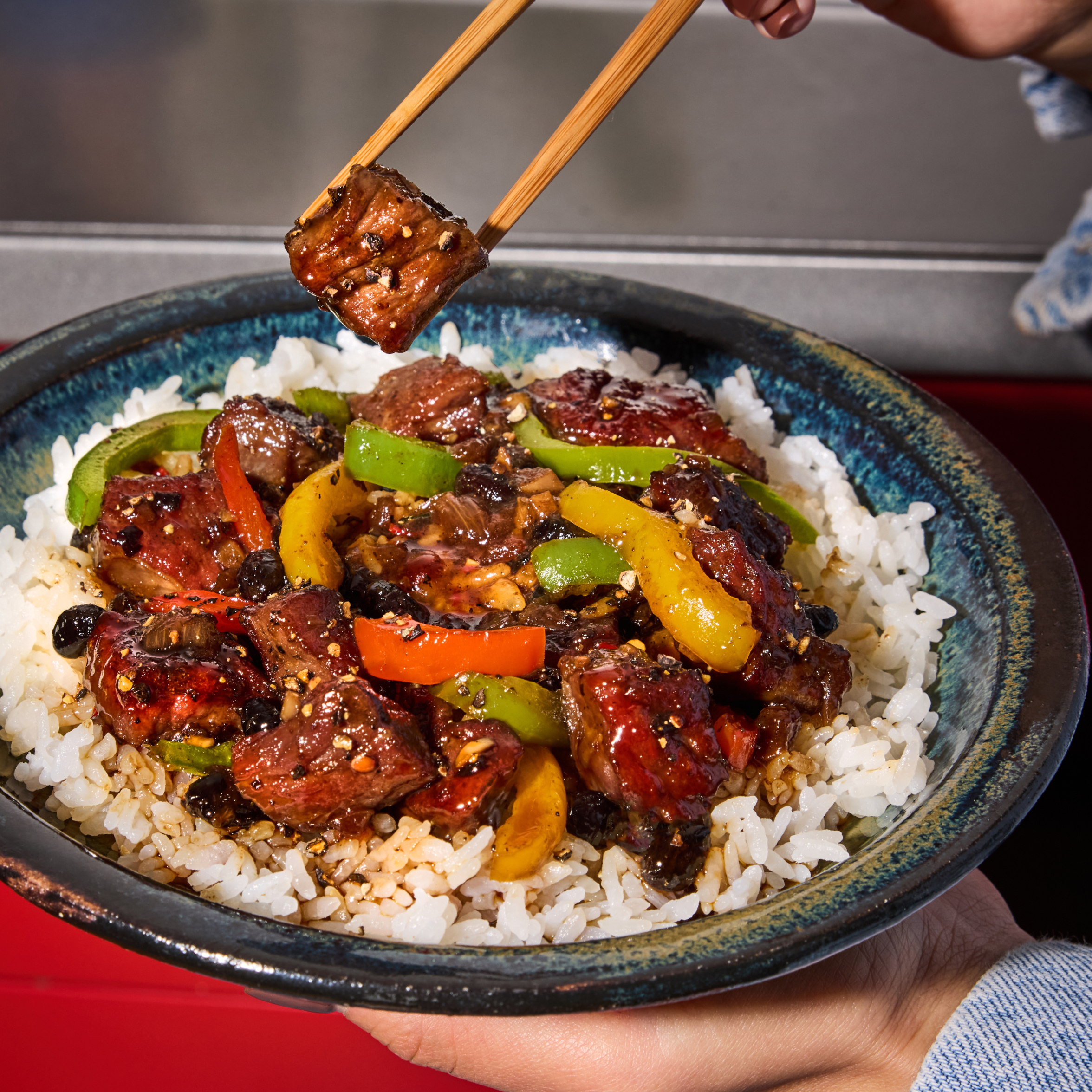 Close-up of Rice Bowl from the Rice Bowl Variety Pack showcasing glazed pepper beef and bell peppers over steamed white rice with chopsticks